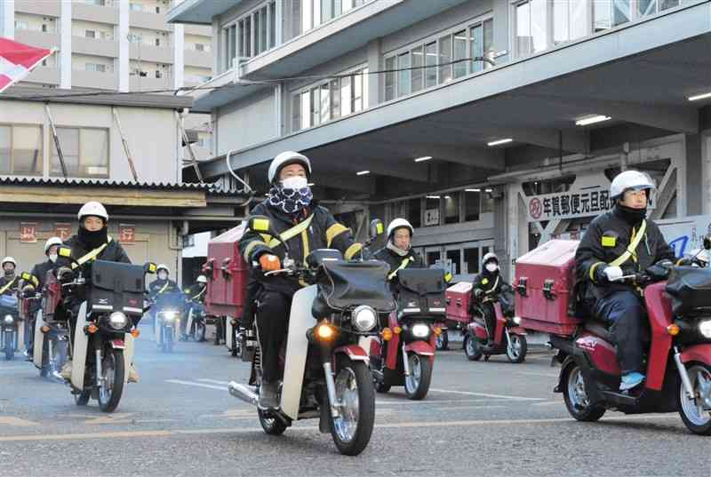 年賀状を積み、バイクで一斉に配達に向かう熊本中央郵便局の局員ら＝1日、熊本市中央区