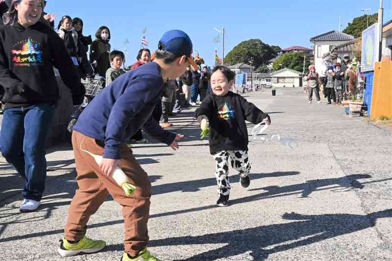 小さな湯島大根を握り締め、笑顔で走る子ども＝1日、上天草市