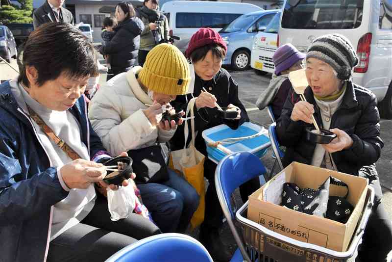 「もとやスーパー」であった餅つきイベントで振る舞われた餅を食べる住民ら＝1日、石川県輪島市