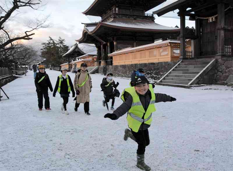 雪景色の中を元気に登校する一の宮小の児童ら＝10日午前7時半ごろ、阿蘇市