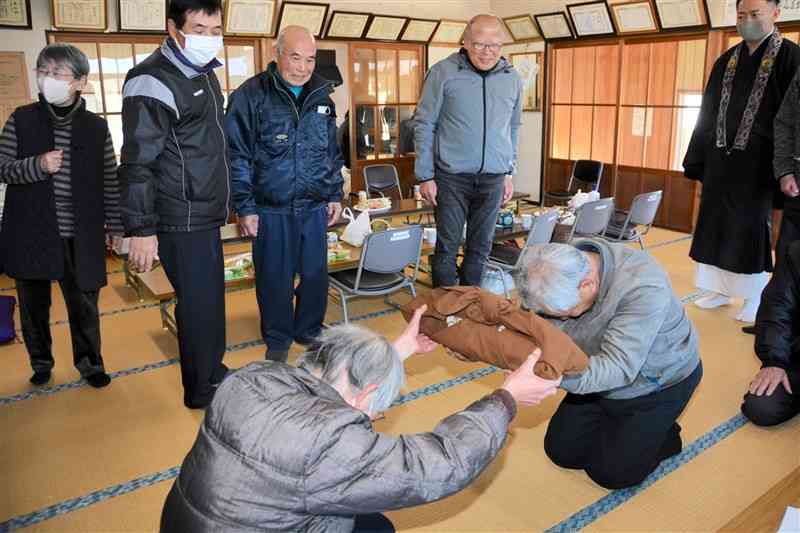 あさぎり町・塚脇地区の門徒（手前左）が掛け軸を錦町・十日市地区の門徒へ手渡した＝10日、あさぎり町