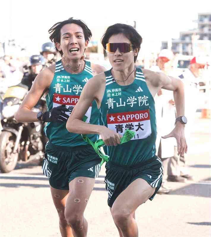 4区の選手にたすきを渡す青学大3区の鶴川正也選手（左、九州学院高出）。右胸には「水上村」のロゴがある＝2日、神奈川県平塚市（代表撮影）