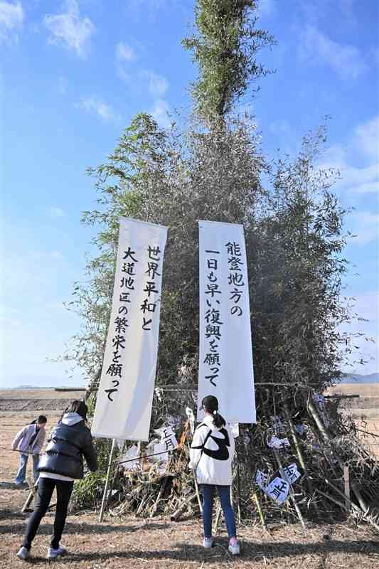 世界平和などのメッセージを掲げたやぐらに火をつける子どもたち＝11日、山鹿市