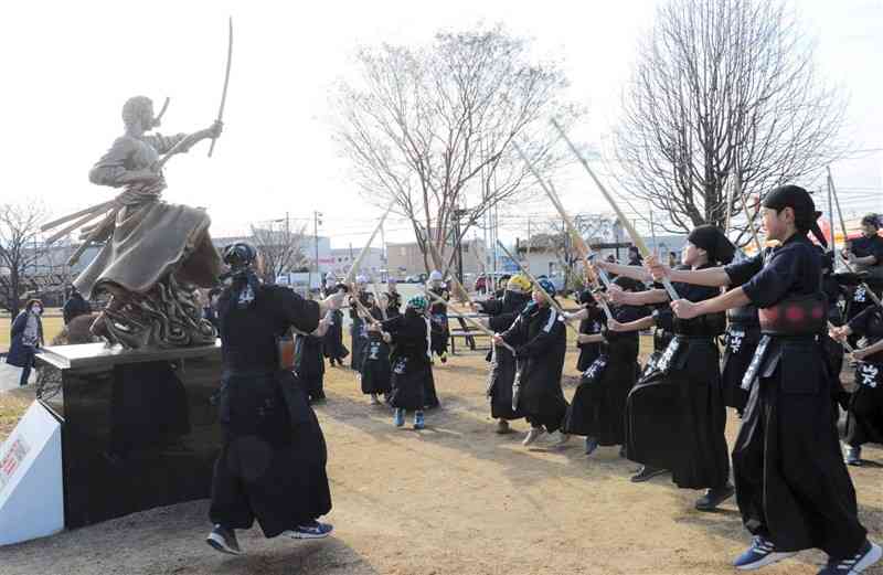 ゾロ像に向かい、竹刀を振る小学生ら＝11日、大津町