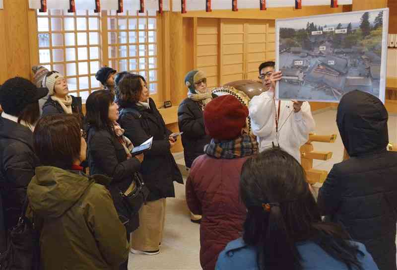 阿蘇神社の神職から話を聞く参加者たち＝12日、阿蘇市