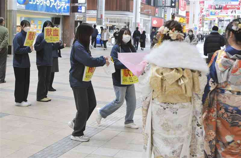 「成人の日」に合わせて晴着姿の若者に献血を呼びかける学生たち＝13日、熊本市中央区