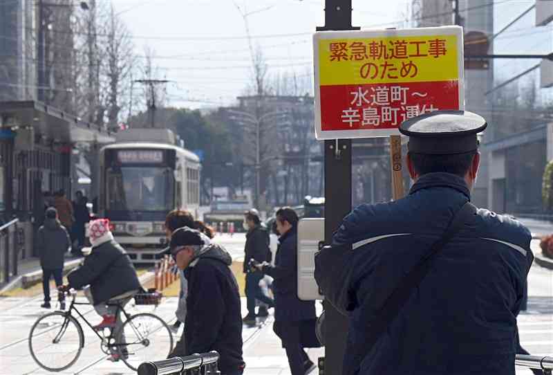 熊本市電の水道町－辛島町間の運休を知らせる看板を手に観光客らを誘導する市交通局の職員＝15日午後1時ごろ（上杉勇太）