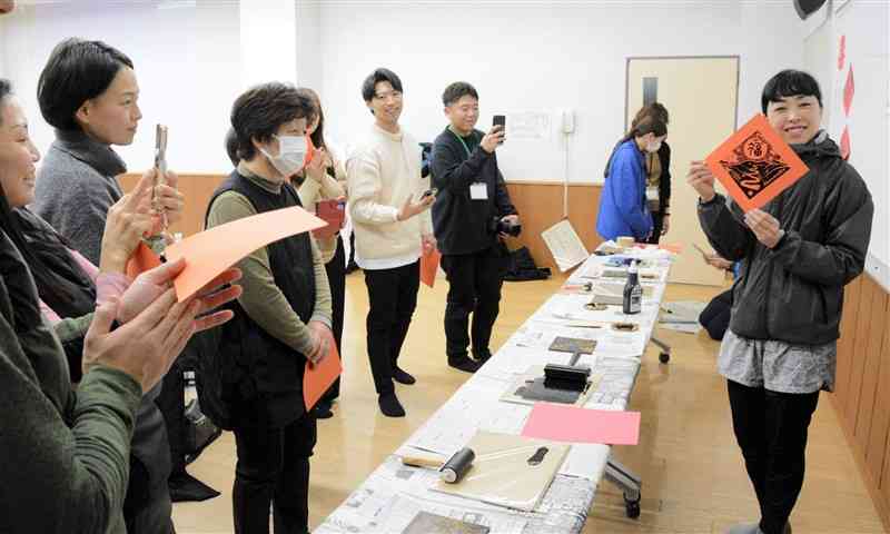 台湾ワークショップで、正月飾りの版画を作ってみせる阿蘇市地域おこし協力隊員の大谷友花さん（右）＝16日、阿蘇市