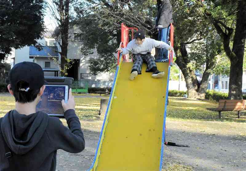 水道端公園で滑り台を撮影する大江小の児童＝昨年12月20日、熊本市中央区