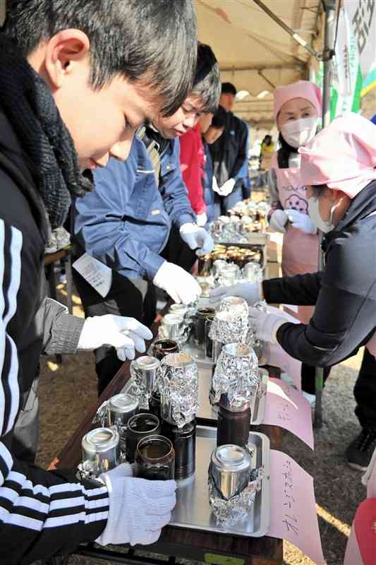 空き缶でコメを炊く方法を学ぶ来場者＝17日、山鹿市