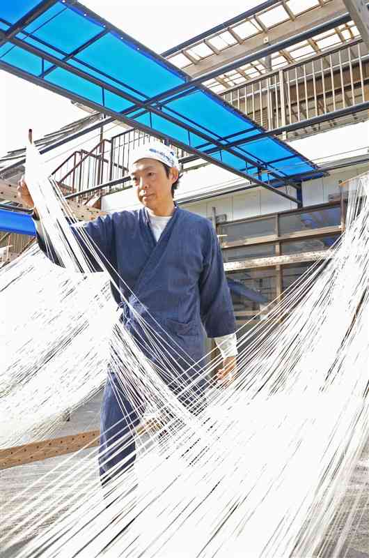 長さ約4メートルに延ばしたそうめんを天日干しする諸富慶太朗さん＝17日、南関町