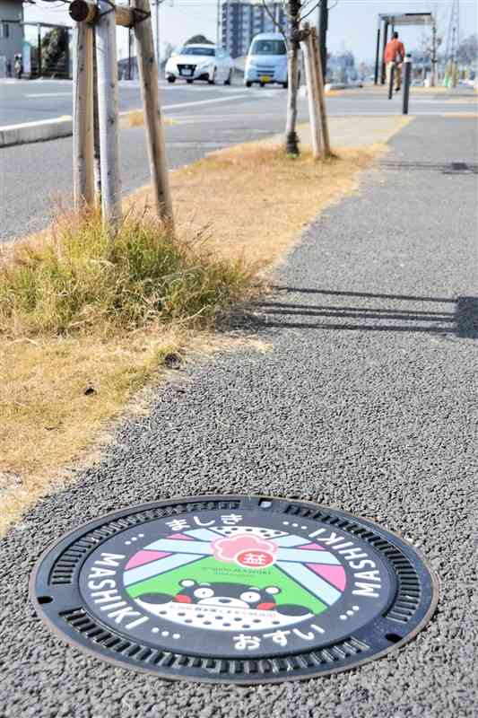 県道熊本高森線の歩道に設置されたくまモンのマンホールふた＝20日、益城町