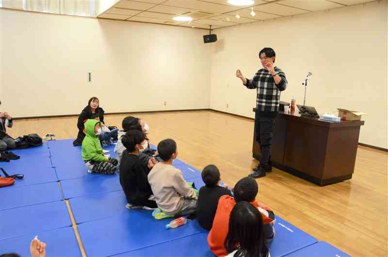 子どもたちの前でマジックを披露する天草ショーゴさん（右）＝18日、天草市