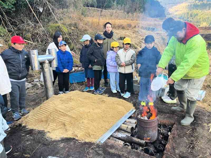 昔ながらの炭作りを体験する久木野小児童ら＝20日、水俣市