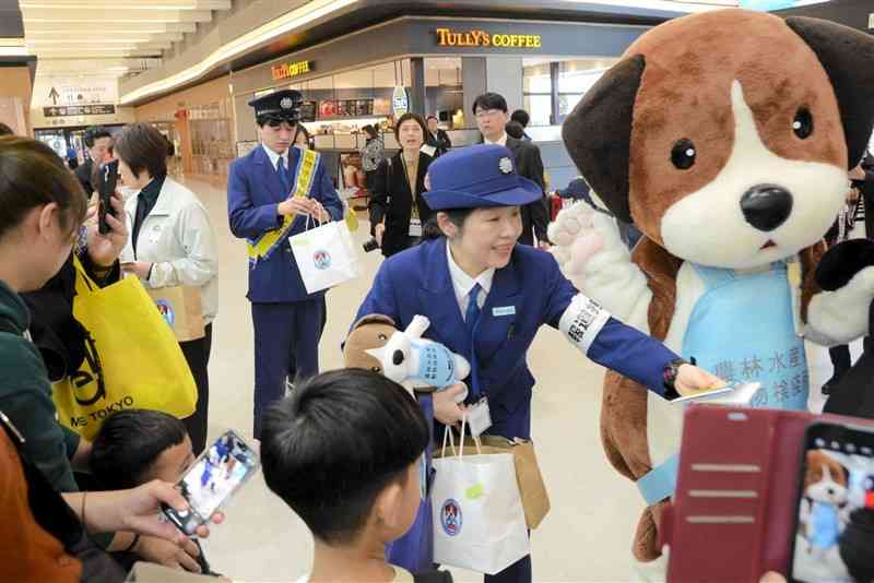 熊本空港利用者にチラシやティッシュを配って肉製品の持ち込み禁止を呼びかける動物検疫所の職員＝23日、益城町