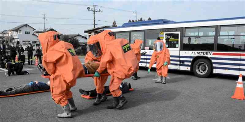 化学テロ対処訓練でバス車内から乗客を救出する消防隊員ら＝23日、合志市