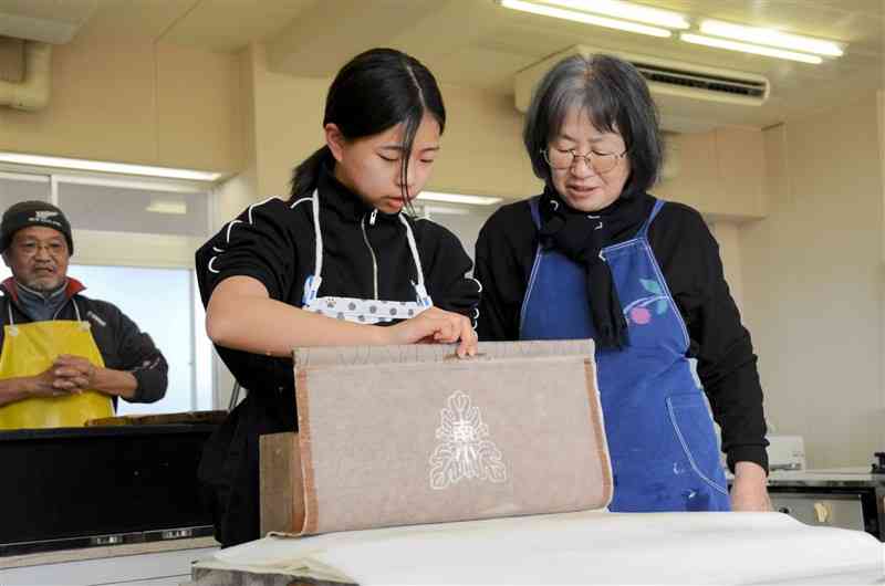 すき終えた和紙を簀桁から慎重に外す児童＝23日、菊陽町