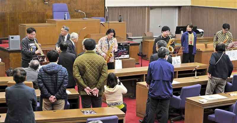 荒尾市議会議場で、市議や職員を前に演奏する「モデトロ」＝30日、同市