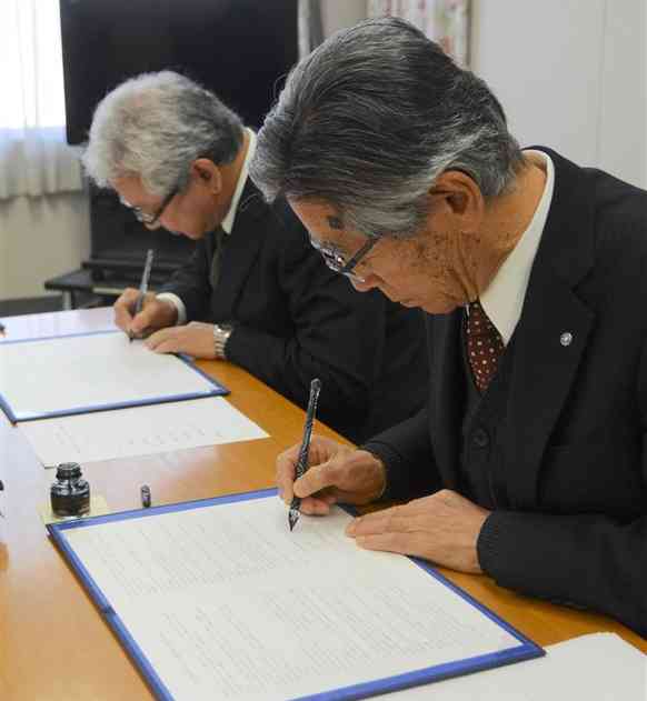 協定書に署名する錦町の森本完一町長（右）と人吉農芸学院の小林健治院長＝31日、錦町