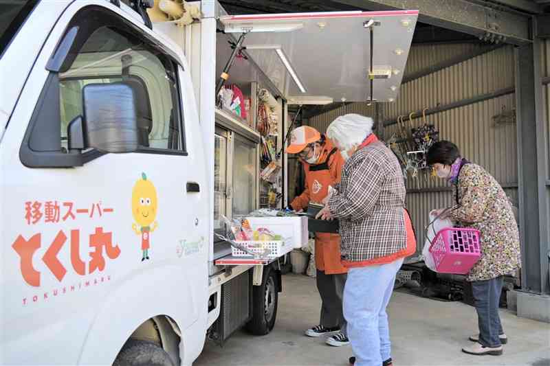 住宅の敷地内に乗り入れた移動販売車「とくし丸」で買い物するお年寄り＝1月21日、長洲町