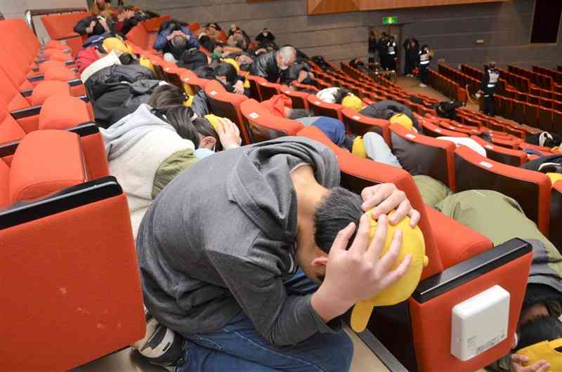 弾道ミサイル飛来を想定した訓練で、しゃがんで身を守る小学生や町民ら＝3日、御船町