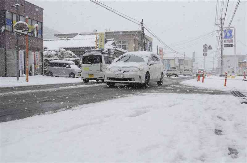 積雪した人吉市街地。屋根に雪を載せた車が行き交った＝5日午後1時10分ごろ（金村貫太）