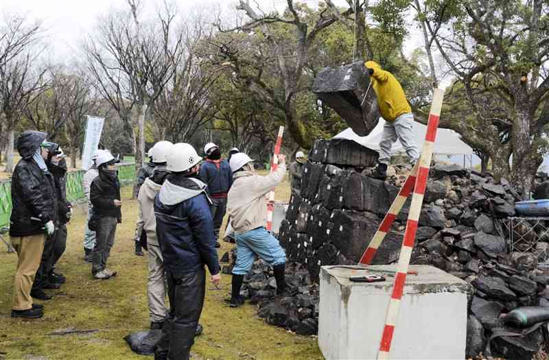 熊本城の石垣復旧技術を学ぶ研修会で、石垣の解体手順を確認する参加者ら＝7日、熊本市中央区