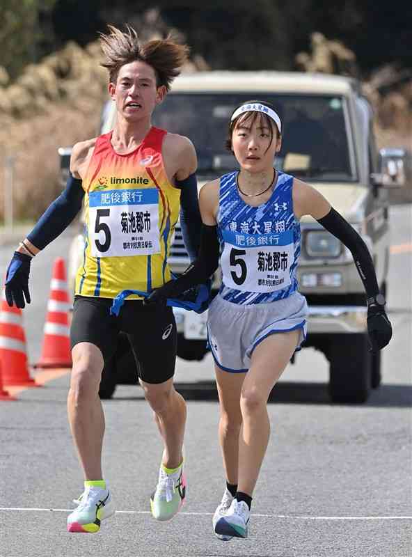 第11中継所、菊池郡市の佐藤大和（左、日本リモナイト）が廣川楓華（東海大星翔高）にたすきをつなぐ＝宇城市（上杉勇太）