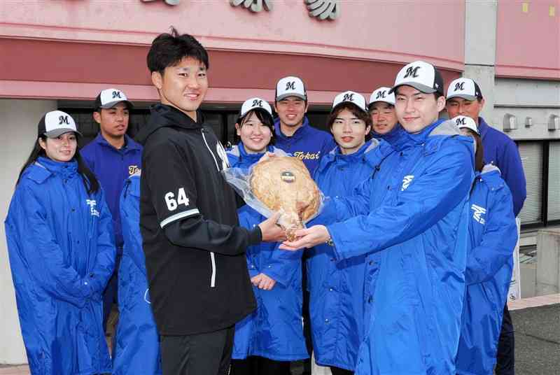 母校の東海大農学部の学生から骨付きハムを贈られるロッテの廣池康志郎投手（左）＝都城市運動公園野球場