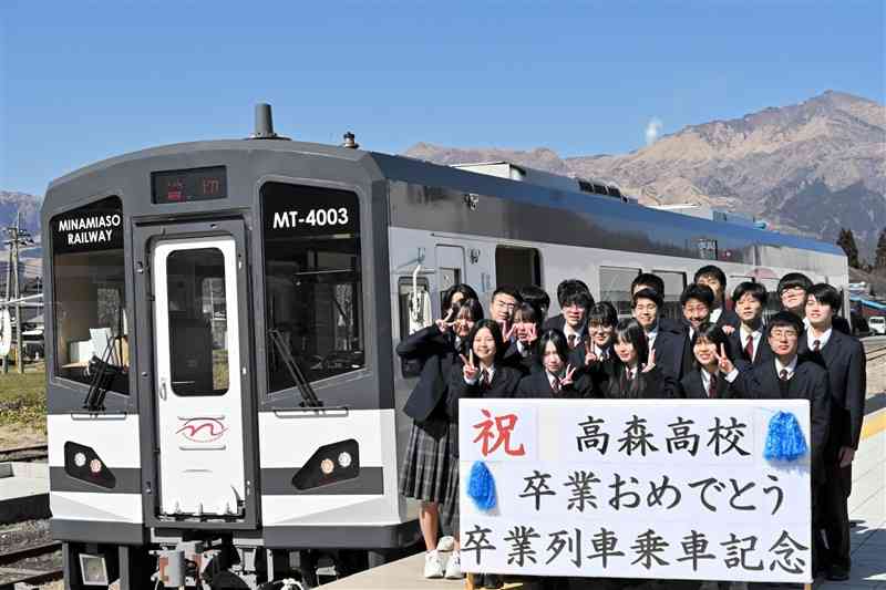 南阿蘇鉄道の列車と記念撮影する高森高の3年生＝14日、高森町