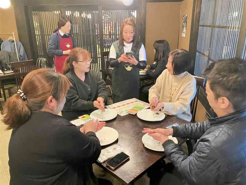 湯の鶴温泉街で和紅茶の手もみ作業を体験するモニターツアーの参加者＝13日、水俣市