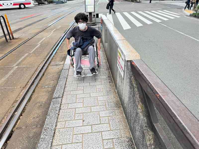 車いすに乗り、熊本市電の電停の使い勝手を調べる熊本学園大の吉田彬人さん（吉田さん提供）