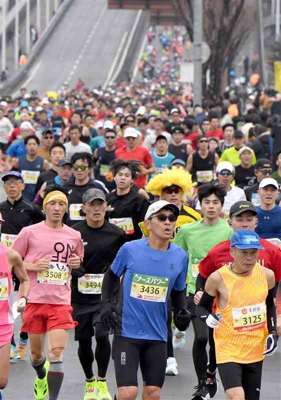 熊本西大橋から続く直線のコースを埋めるフルマラソンのランナーたち＝16日午前9時55分ごろ、熊本市南区（小野宏明）