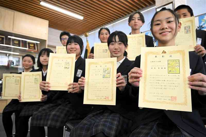 自分の作品が入った表彰状を受け取った児童たち＝19日、山鹿市