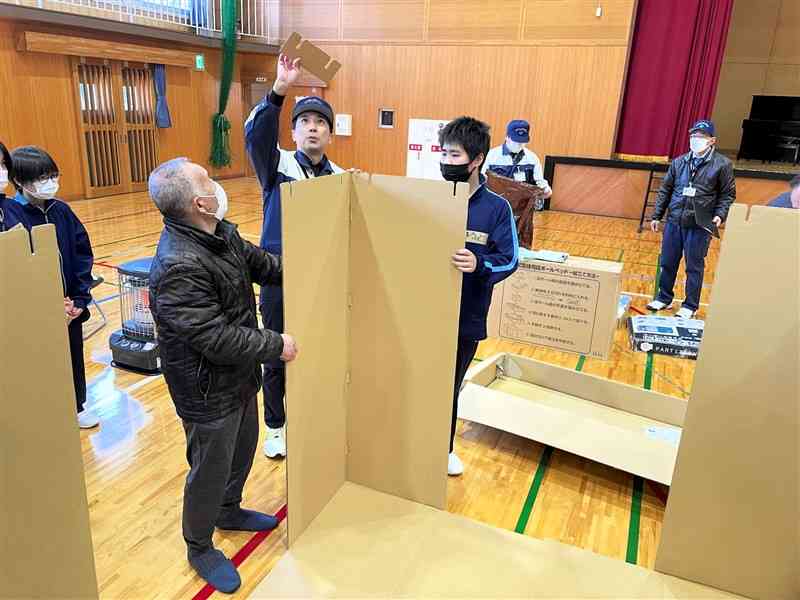 段ボール製の間仕切りの使い方を学ぶ八代市坂本町の住民や中学生＝20日、同市