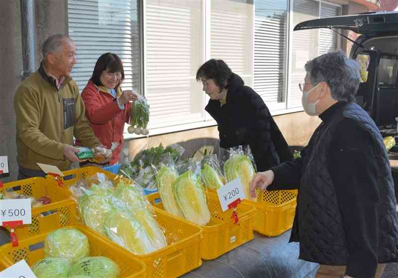 軽トラックの荷台に並べた野菜を販売する嶽本理一さん（左）と西本和代さん（左から2人目）＝20日、水俣市