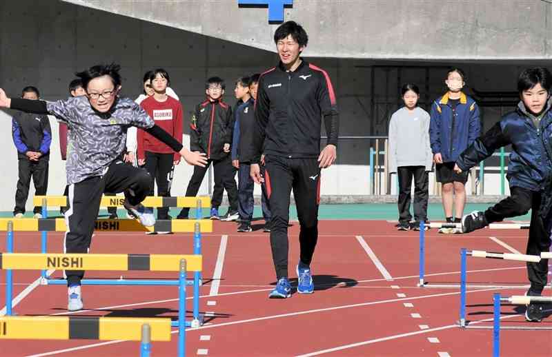 小学生にハードルの跳び方を教える筒江海斗選手（中央）＝えがお健康スタジアム